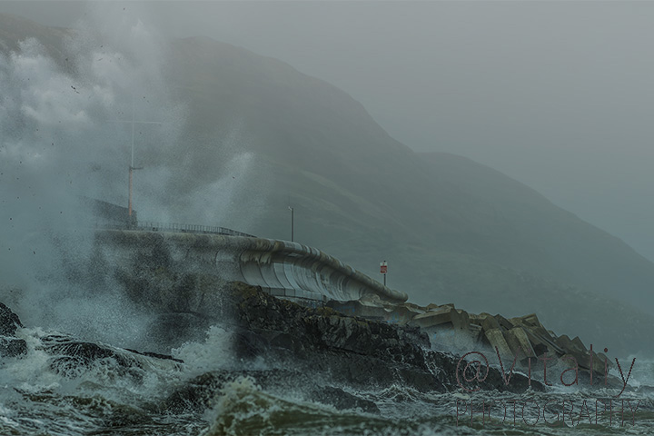 Sea waves crushing over rocks of Greystones Cove with Bray Head on background. Irish scenery photography.